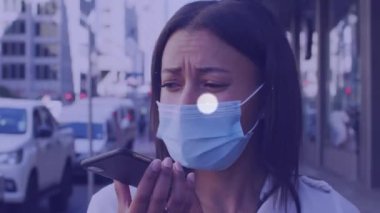 Animation of network of connections over biracial woman in face mask using smartphone. Business, connections, communication and technology concept digitally generated video.