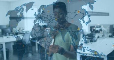 Animation of world map and icons over african american woman working in office. Business, finance, economy and technology concept digitally generated video.