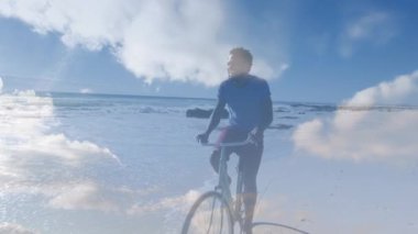 Animation of clouds over happy african american man with bike on beach. Holidays, vacations and relax concept digitally generated video.