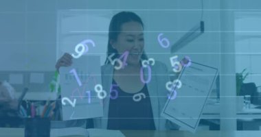 Animation of numbers changing over happy asian woman making presentation. Business, finance, economy, data processing and technology concept digitally generated video.