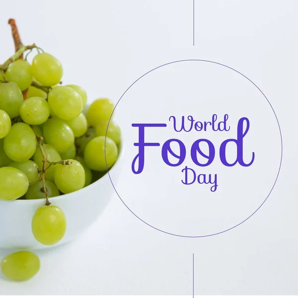 Image of world food day over grapes in bowl on white background. Food, nutrition, agriculture, health and food production concept.