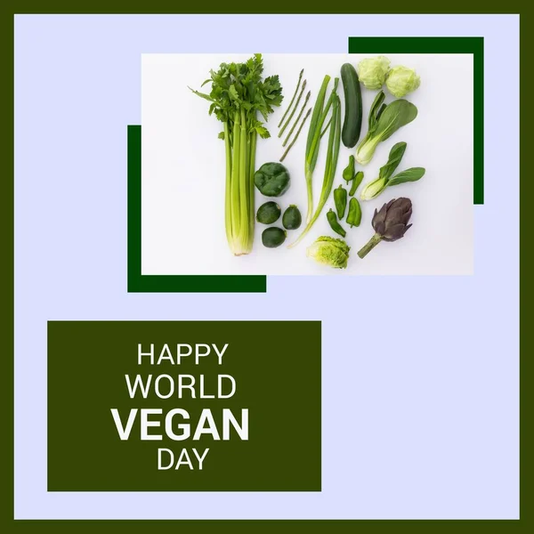 Composition of happy world vegan day text with vegetables on blue background. World vegan day and celebration concept digitally generated image.