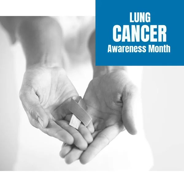 Image of lung cancer awareness month over hands of caucasian senior woman holding ribbon. Health, medicine and cancer awareness concept.