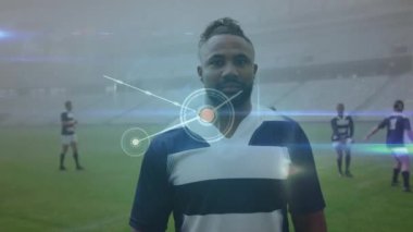 Animation of network of connections over african american male rugby player standing on sports field. Global networking and sports technology concept