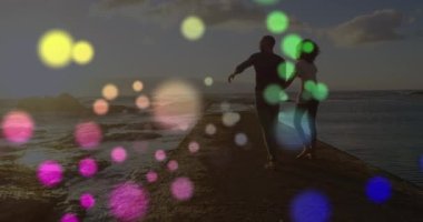 Afrika kökenli Amerikalı bir çiftin deniz kenarındaki kayalarda yürüdüğü renkli ışık noktalarının animasyonu. Aşk ve ilişki kavramı
