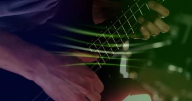 Animation of glowing green light trails over mid section of caucasian man playing guitar. Music, performance and entertainment concept.