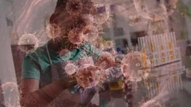Animation of covid 19 cells floating over african american boy in science lab. Global covid 19 pandemic and healthcare concept digitally generated video.