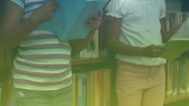 Animation of falling confetti over diverse girl in library. Learning and education concept digitally generated video.