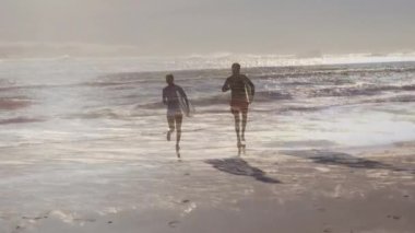 Sahilde sörf tahtası olan Afro-Amerikan bir çift üzerinde deniz animasyonu. Tatil ve dijital arayüz kavramı dijital olarak oluşturulmuş video.