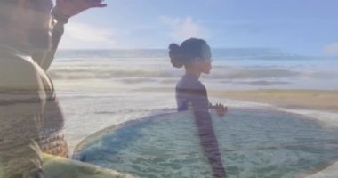 Sahilde sörf tahtası olan Afro-Amerikan bir çift üzerinde deniz animasyonu. Tatil ve dijital arayüz kavramı dijital olarak oluşturulmuş video.