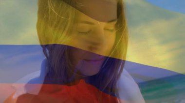 Animation of flag of colombia over caucasian woman at beach. National flags, patriotism and holiday concept digitally generated video.