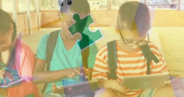 Animation of puzzle pieces over diverse schoolchildren using tablet. autism awareness month and celebration concept digitally generated video.