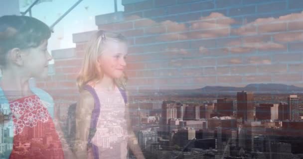 学校で手をつないで歩く2人の白人の女の子に対する都市の景色の複合ビデオ 学校や教育の概念 — ストック動画