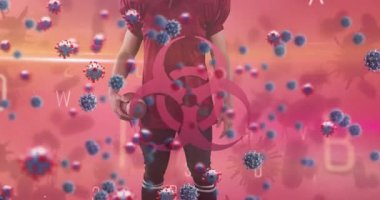 Animation of falling covid 19 cells over american football player. Global covid 19 pandemic, science and connections concept digitally video.