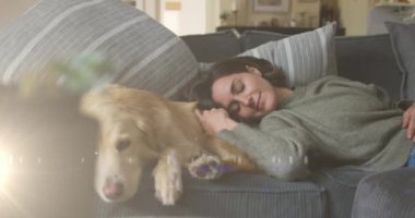 Spot of light against caucasian woman sleeping with her dog on the couch at home. national pet month awareness concept