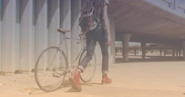 Spots of light against rear view of african american man with bicycle walking. pedal day awareness concept