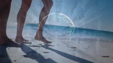 Animation of globe, numbers, rays against caucasian couple walking barefoot at sunny beach. Digital composite, multiple exposure, digital interface, technology, global science, wellbeing, leisure time