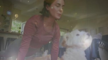 Spot of light against caucasian woman performing yoga while her dog sitting next to her at home. national pet month awareness concept