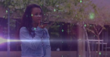 Animation of green arrows and data processing over smiling biracial woman using smartphone outdoors. Global communication, business, data and digital interface concept digitally generated video.