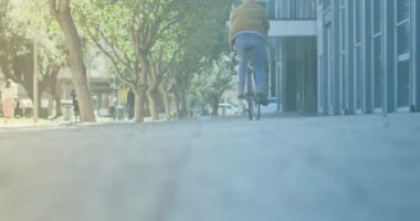 Spots of light against rear view of a man riding a bicycle on the street. pedal day awareness concept