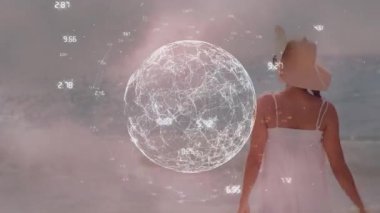 Sahilde duran şapkalı kadının dikiz aynasından dönen dijital küre ve sayıların animasyonu. Dijital bileşim, çoklu pozlama, küreselleşme, tatil, keyif ve doğa kavramı.