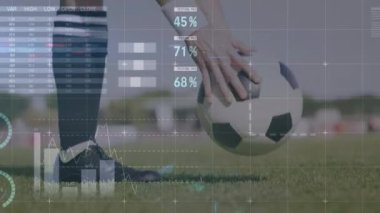 Animation of graphs and financial data over legs of male soccer player with ball on field. Sport, soccer, finance and economy concept digitally generated video.