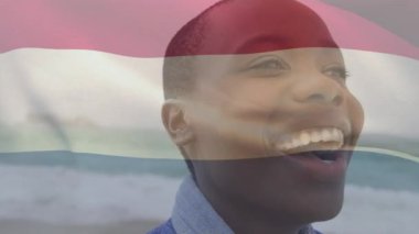Sahildeki Afrikalı Amerikalı bir kadın üzerinde Hollanda bayrağının animasyonu. Ulusal bayraklar, vatanseverlik ve dijital olarak üretilen tatil konsepti.