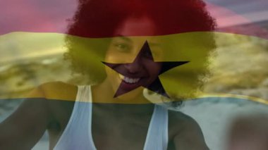 Animation of flag of ghana over african american woman at beach. National flags, patriotism and holiday concept digitally generated video.