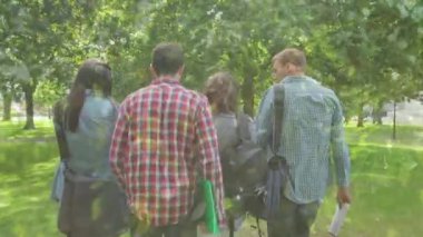 Composite video of close up of leaves against rear view of group of people walking in the garden. nature concept
