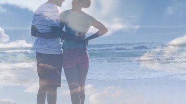 Sahildeki Afro-Amerikan çifti üzerindeki bulutların animasyonu. Tatil ve dijital arayüz kavramı dijital olarak oluşturulmuş video.