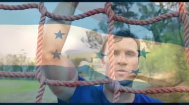 Animation of flag of honduras over caucasian man during obstacle race training. national sports, activity and patriotism concept digitally generated video.