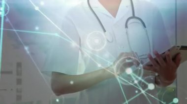 Animation of dots interconnecting with lines over smiling caucasian female doctor using tablet. Digital composite, multiple exposure, technology, telecommunication, healthcare and medical concept.