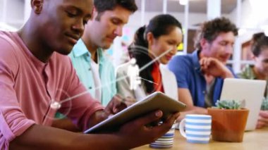 Animation of digital icons over portrait of african american man using digital tablet at office. Global networking and business technology concept