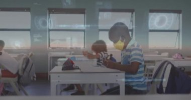 Animation of data processing over african american boy wearing face mask raising his hand at school. Covid-19 pandemic and school education technology concept