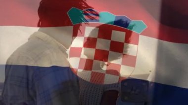 Animation of croatia flag waving over happy african american couple embracing at beach. Digital composite, multiple exposure, togetherness, love, nature, patriotism and identity concept.