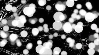 Animation of grey and white spots of light over light on moving shiny black plastic. Creativity, imagination and change, monochrome abstract background concept digitally generated video.