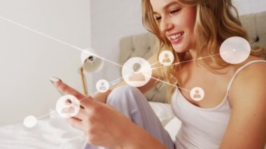 Profil simgeleri, yatakta cep telefonu kullanan, gülümseyen, beyaz bir genç kadının çizgileriyle kesişiyor. Animasyon, dijital kompozit, çoklu pozlama, teknoloji, yaşam tarzı, ev, telekomünikasyon.