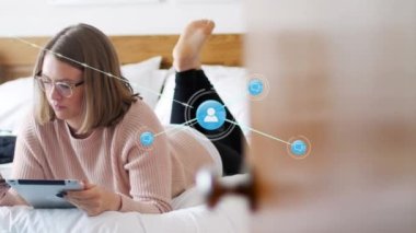 Profile icons connecting with lines over caucasian woman using cellphone and tablet on bed. Animation, digital composite, multiple exposure, home, lifestyle, lying, telecommunications, technology.
