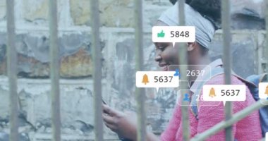 Animation of social media icons over african american woman using smartphone. Global social media, business, data processing and digital interface concept digitally generated video.