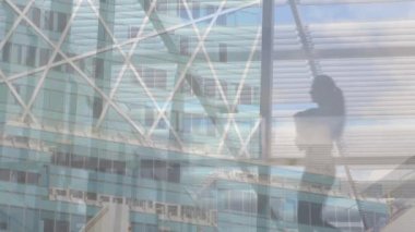 Diverse male and female business people walking in corridor, over cityscape. Communication, diversity, work and business concept digitally generated video.