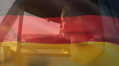Animation of german flag over thoughtful african american woman looking through vehicle window. Digital composite, contemplation, beach, wind, nature, vacation, patriotism and identity concept.