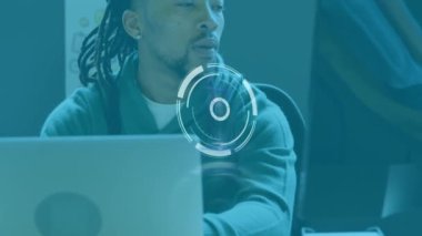 Animation of scanning icon moving over african american businessman with dreadlocks using laptop. Digital composite, multiple exposure, hairstyle, fashion, technology, business and office concept.