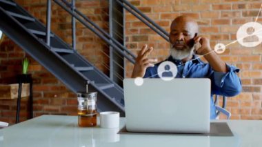 Animation of network of profile icons over african american man talking on smartphone at office. Global networking and business technology concept