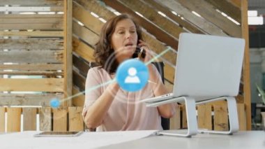 Animation of network of profile icons over caucasian woman talking on smartphone at office. Global networking and business technology concept