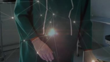 Animation of network of connections over caucasian male surgeon checking medical equipment. Medical healthcare and technology concept