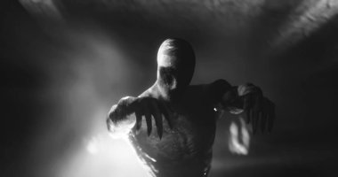 Image of scary zombie mummy walking in dark crypt with burning torches, in black and white. Halloween fear, horror and suspense concept digitally generated image.