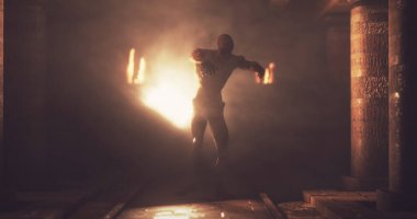 Image of scary zombie mummy walking around in dark crypt room with burning torches. Halloween fear, horror and suspense concept digitally generated image.