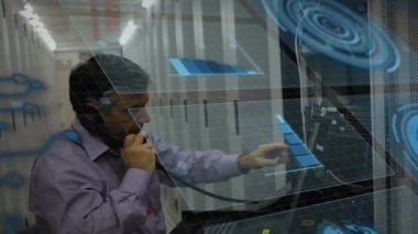 Animation of graphs and data processing over caucasian man on phone working in server room. Global communication, business, data security and digital interface concept digitally generated video.