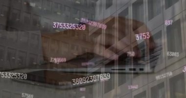 Animation of numbers processing over modern office building and caucasian man using laptop. Global business, data processing and digital interface concept digitally generated video.