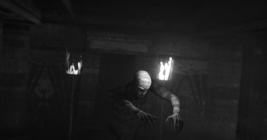 Image of scary zombie mummy walking in dark crypt with burning torches, in black and white. Halloween fear, horror and suspense concept digitally generated image.